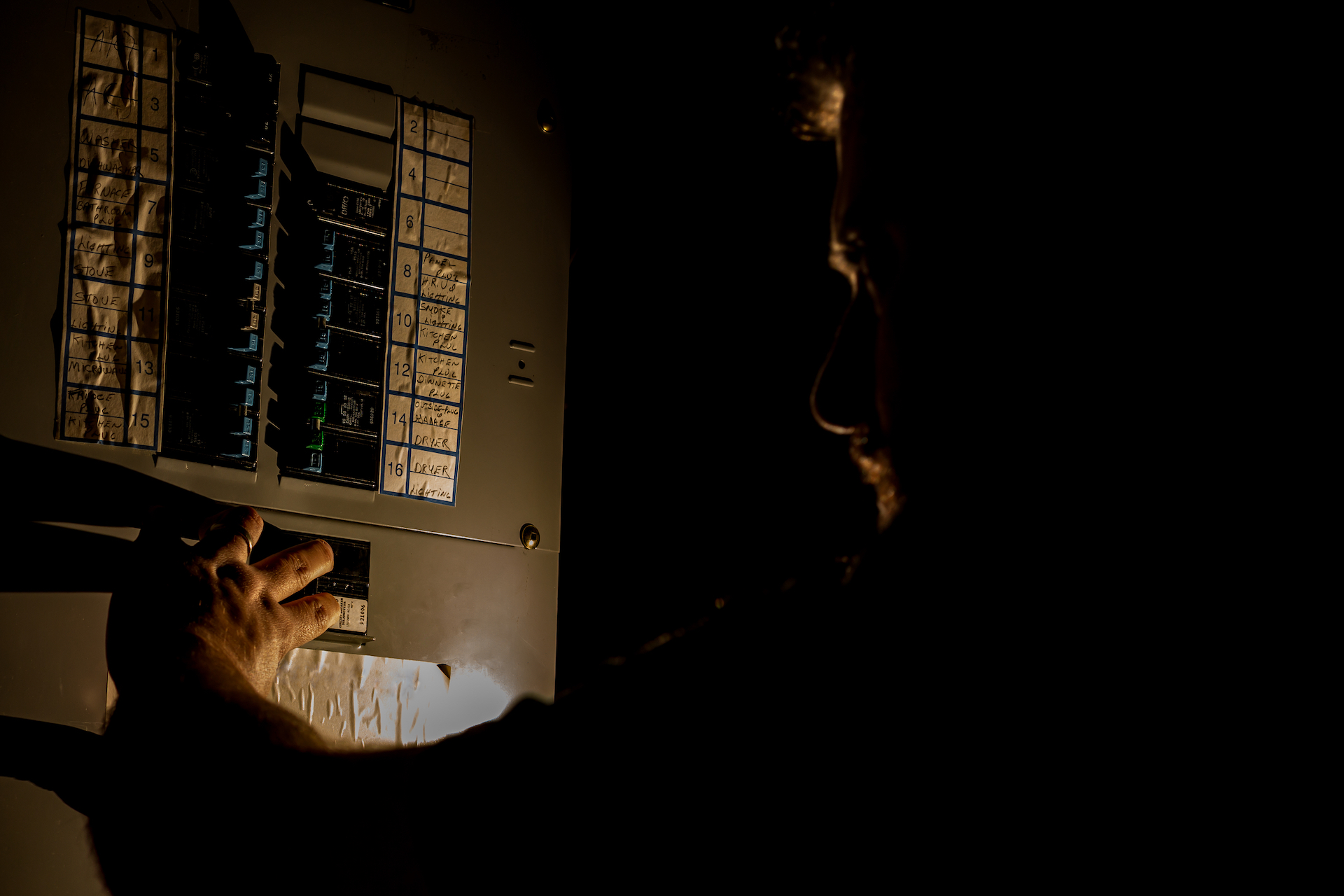 Man visible as a faint silhouette holding flashlight on electrical box