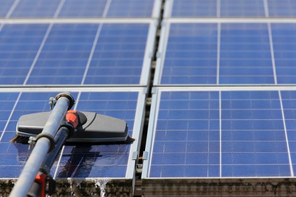 Cleaning solar panels with brush and water